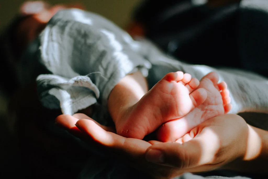 Pés de bebê recém-nascido seguros pelas mãos dos pais